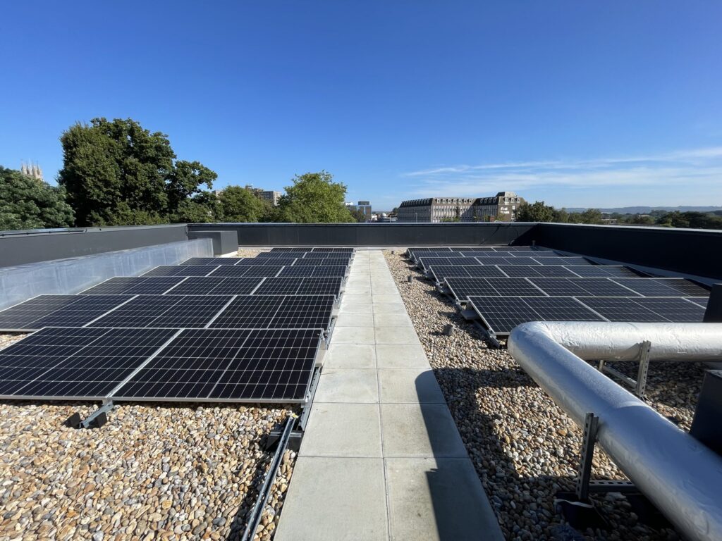 Rooftop solar PV panels installed on a flat commercial building under clear blue sky.